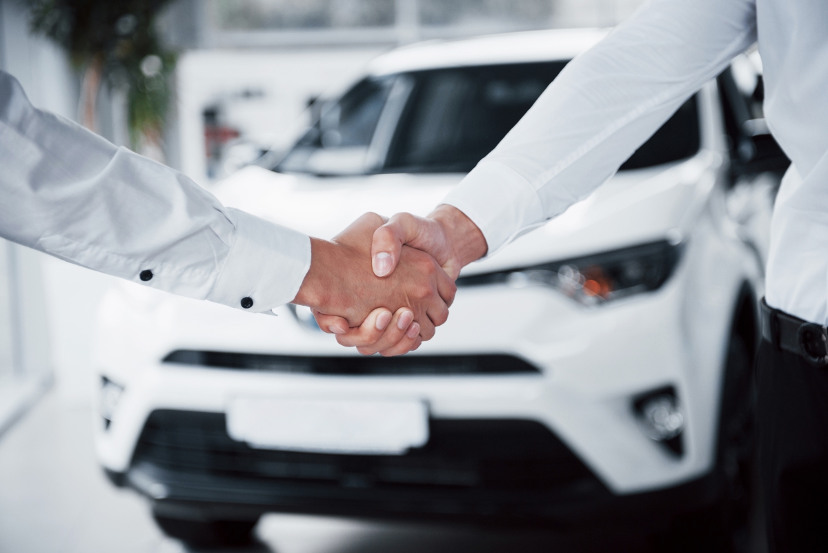 Demande de crédit avec Exo-crédit poignée de main devant un véhicule blanc